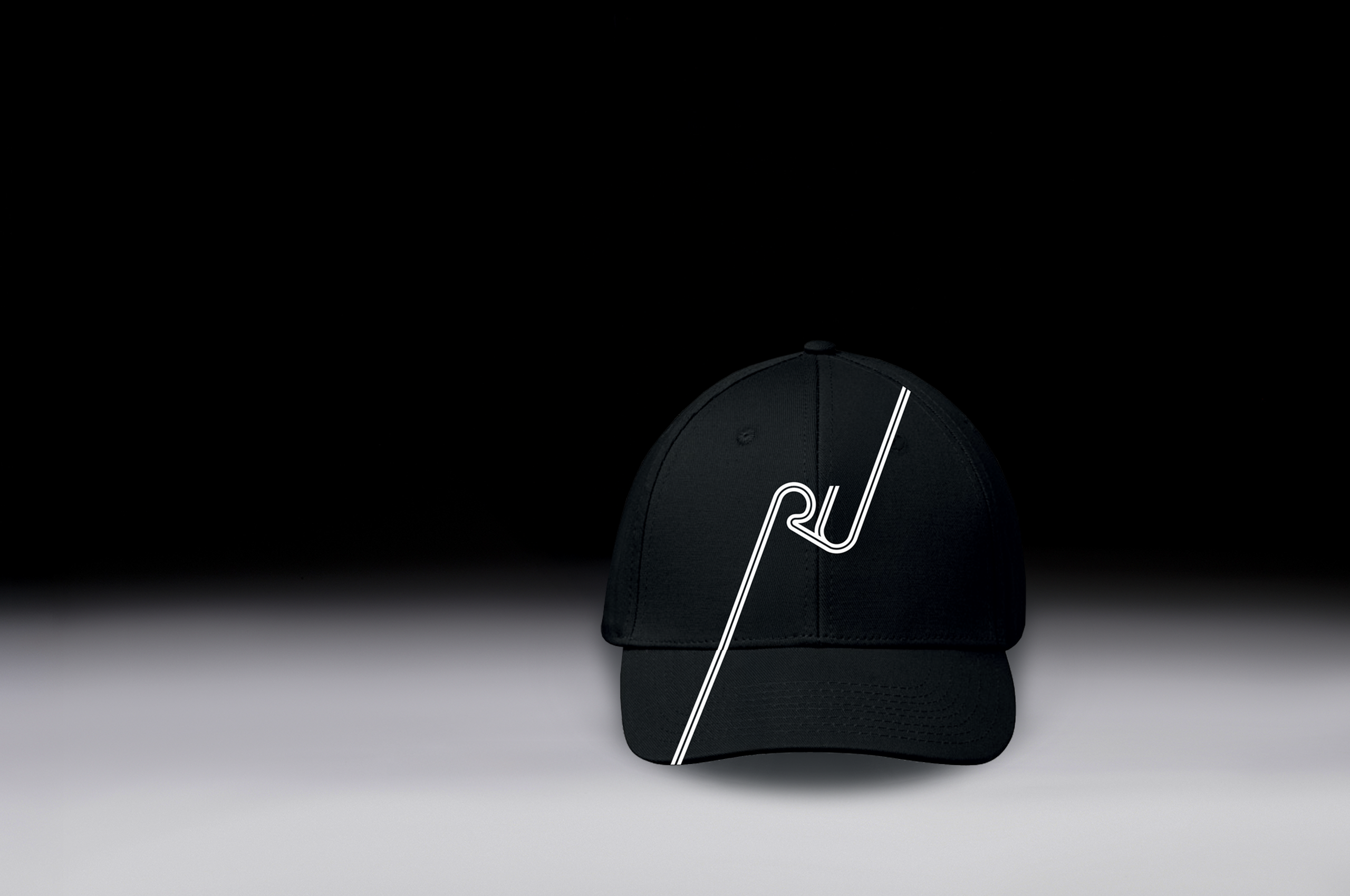 Schwarze Kappe mit Racing Unleashed-Logo auf dunklem Hintergrund.