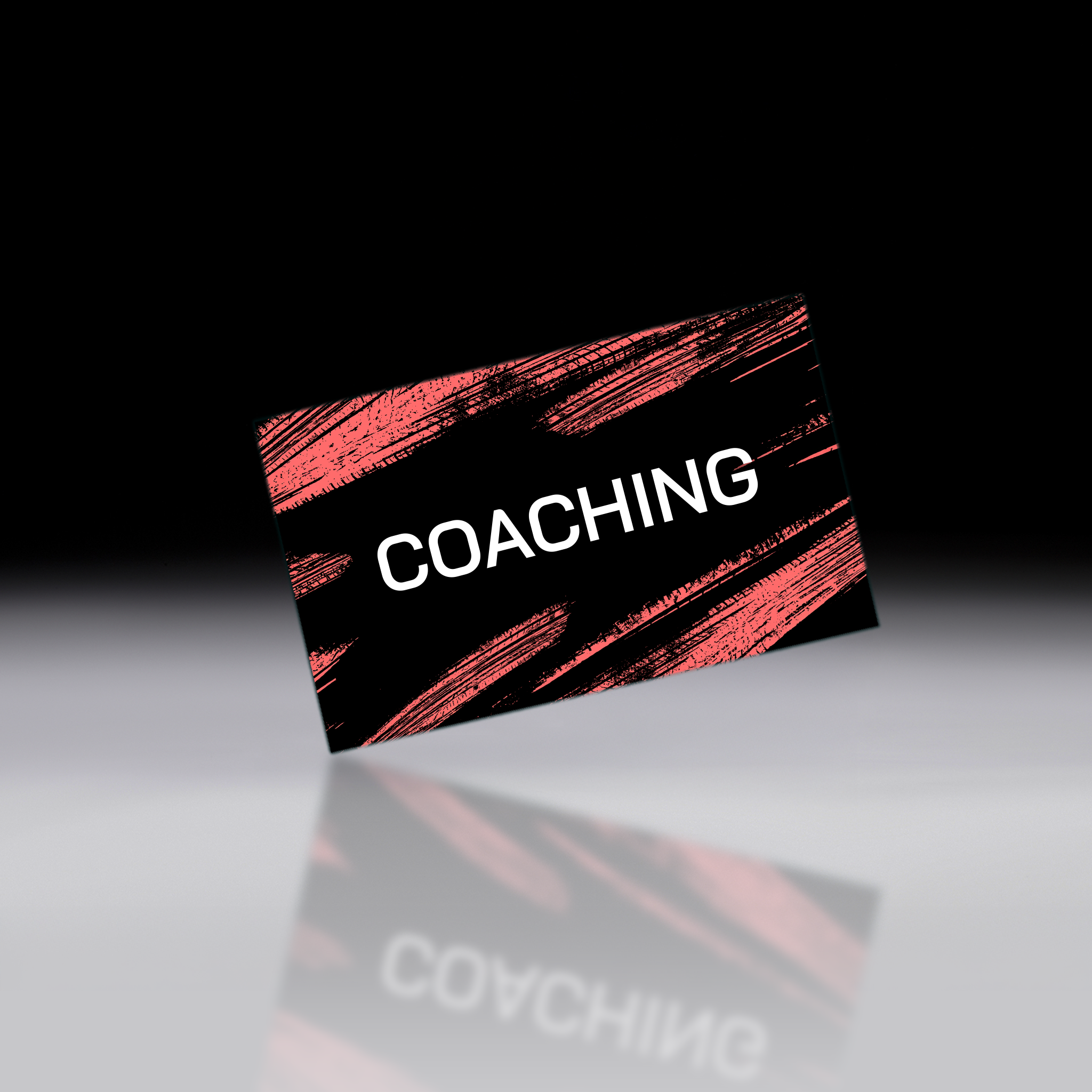A rectangular business card with a black background and textured red brushstroke pattern, featuring the word 'COACHING' in white. The card is shown floating at an angle above a reflective gray surface against a black background.