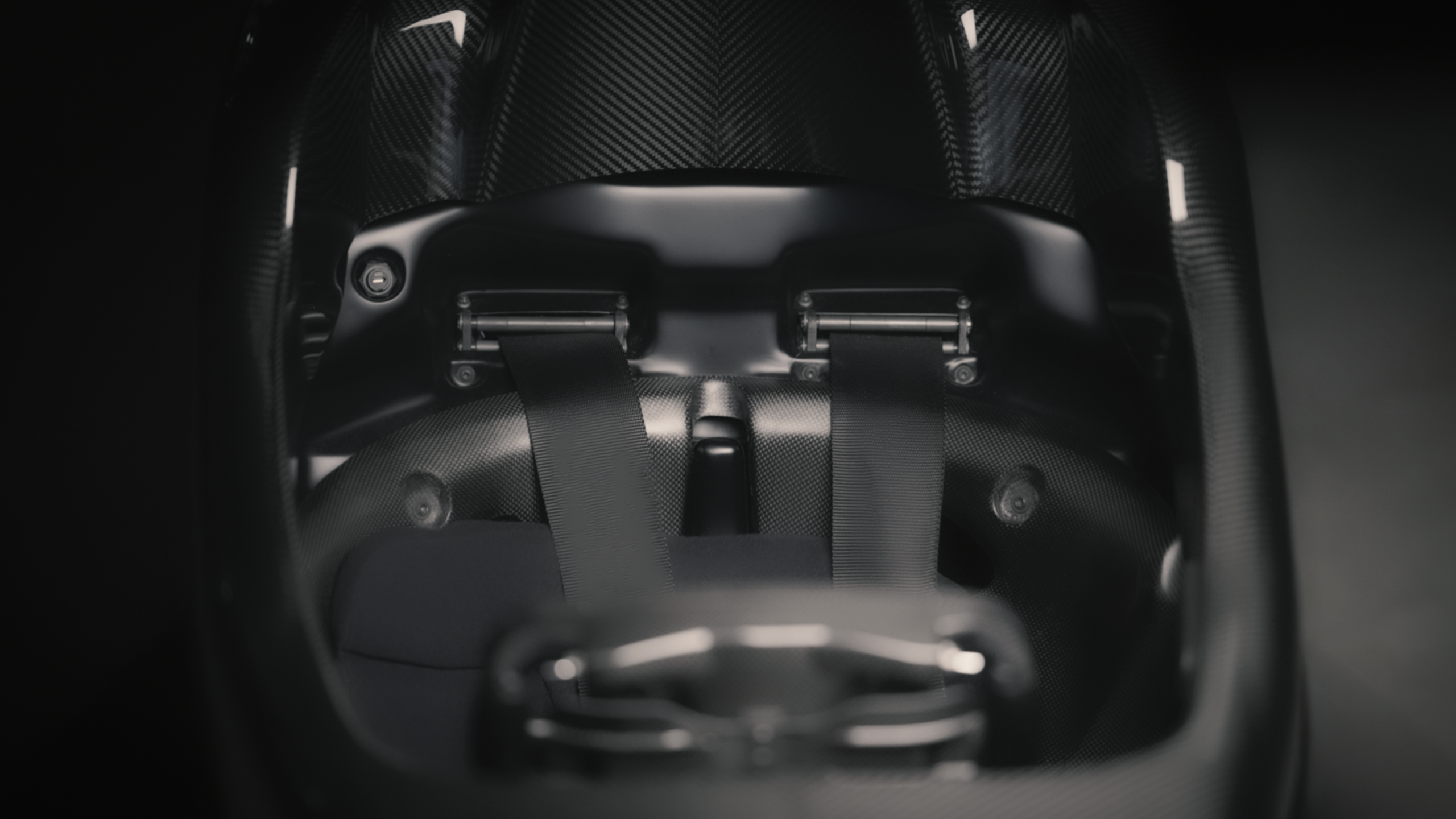 Ein schwarzer Rennsitz aus Carbonfaser von Racing Unleashed mit Sicherheitsgurten.