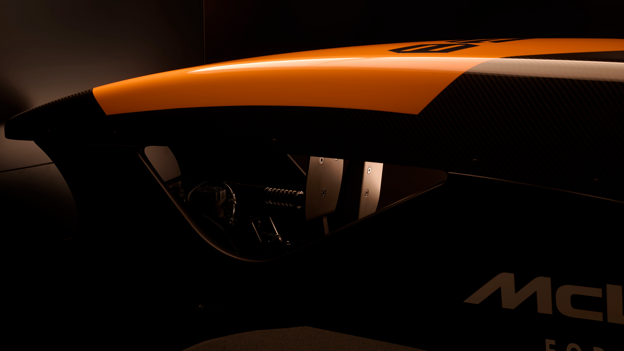 Ein orange-schwarzer McLaren-Rennsimulator von Racing Unleashed in dunkler Umgebung.